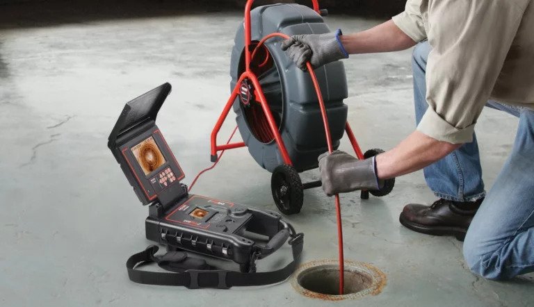 A Drainstar Plumbing Inc. technician feeding a camera cable into a floor drain
